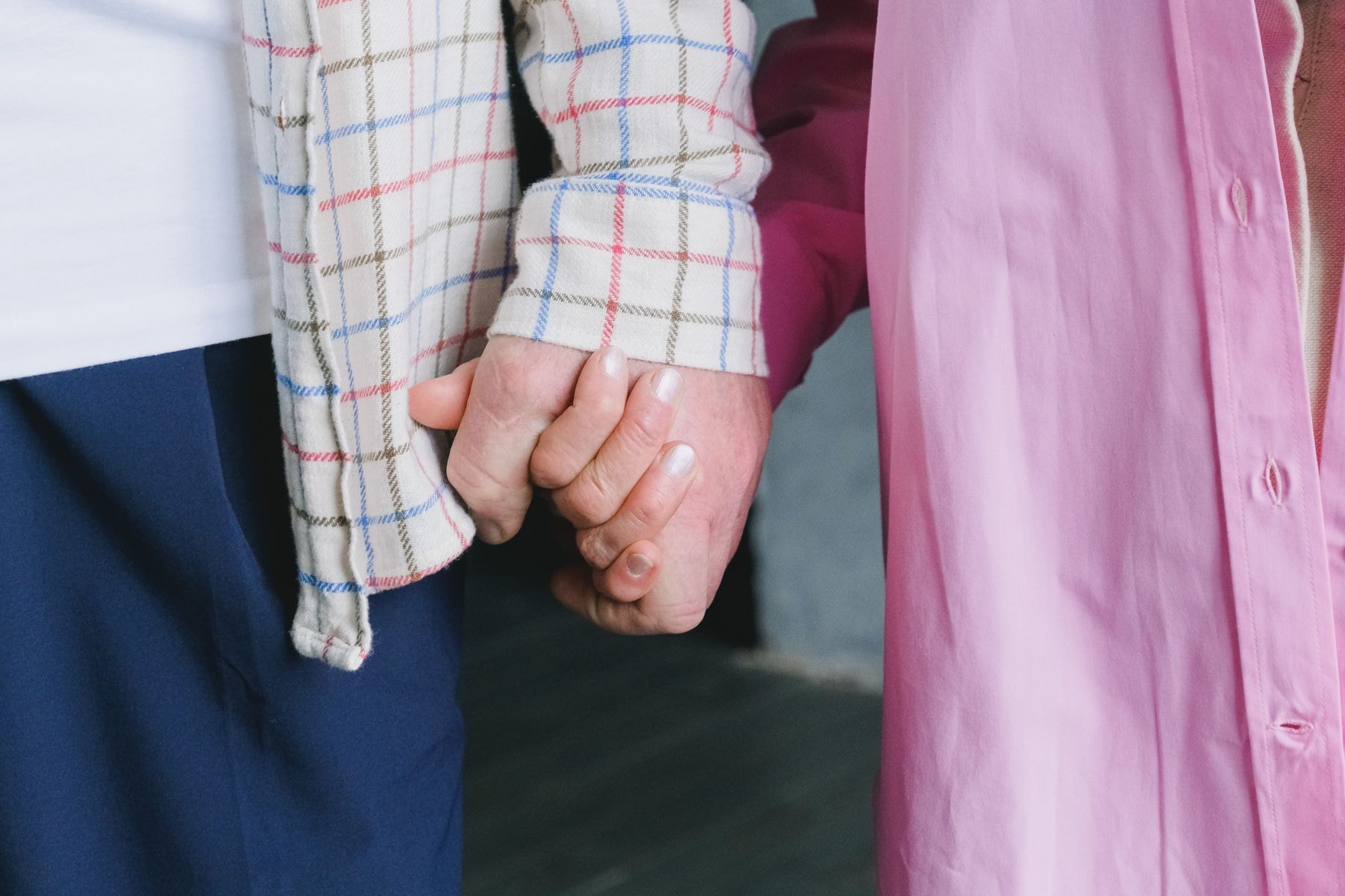 An older couple holding hands in a close-up moment of connection